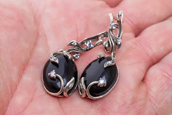Silver earrings with  black agate  on the palm — Stock Photo, Image
