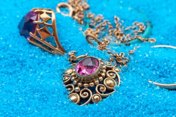 Gold Jewellery in blue sand — Stock Photo, Image