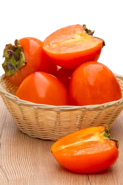 Ripe persimmons in a wicker bowl — Stock Photo, Image