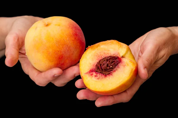 Pfirsiche in den Händen auf schwarz — Stockfoto