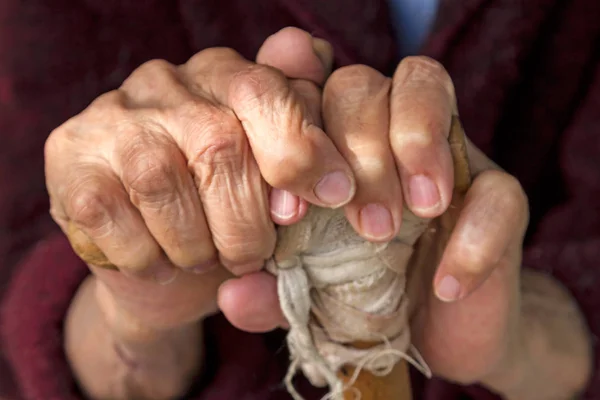 Руки старухи на деревянном костыле — стоковое фото
