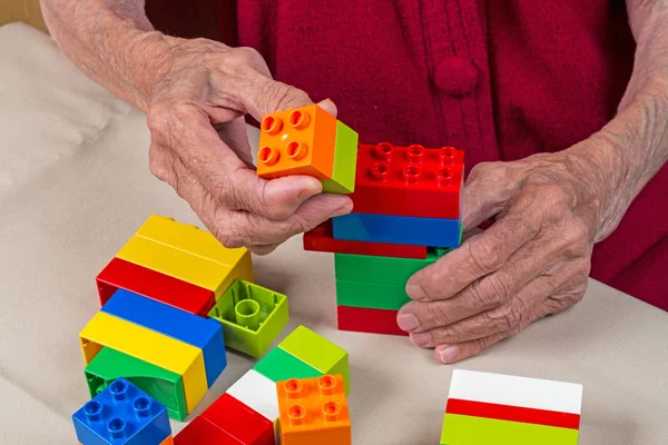 Руки пожилой женщины с пластиковыми блоками — стоковое фото