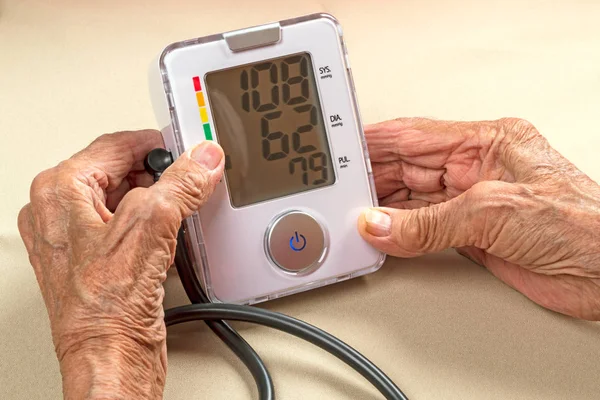 Old woman and digital blood pressure monitor — Stock Photo, Image