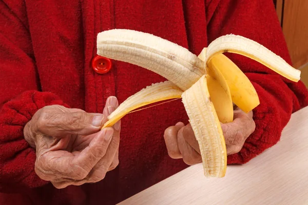 Alte Frau putzt eine Banane — Stockfoto