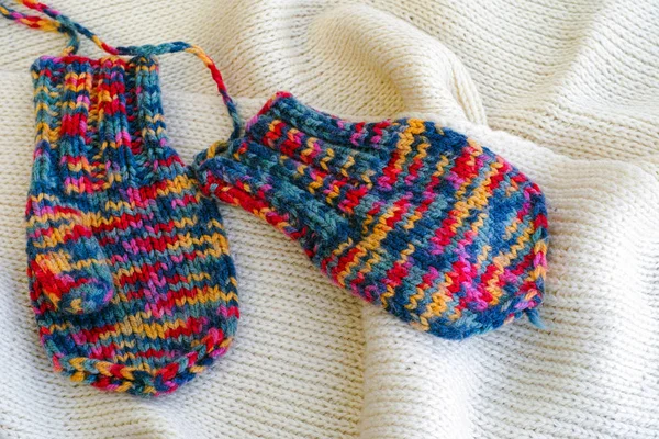 Two multicolored knitted mittens on white scarf — Stock Photo, Image