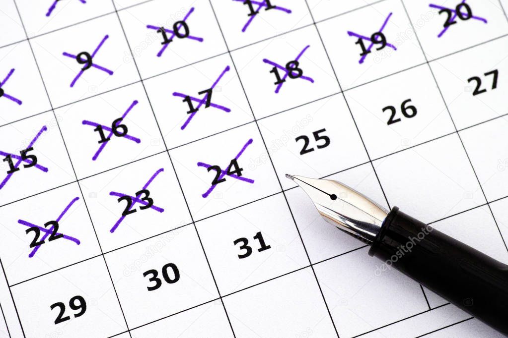 Fountain pen on calendar with marking days