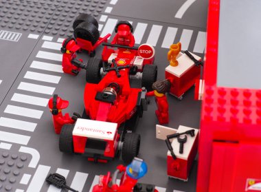 Lego team crew members fixing wheel of Ferrari F14 T race car clipart