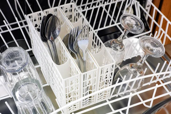 Open dishwasher with spoons, forks and glasses