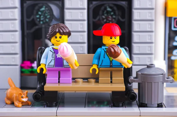 Девочка и мальчик из Lego с мороженым сидят на скамейке — стоковое фото
