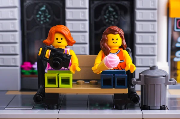 Zwei Lego-Mädchen sitzen auf der Bank in der Lego-Straße — Stockfoto