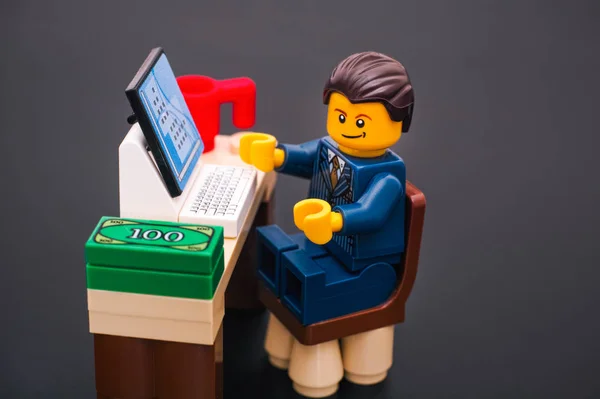 Lego businessman sitting at his working table with computer, mon — Stock Photo, Image