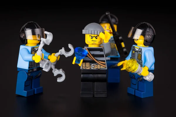Три офицера полиции Лего и грабитель с бриллиантом на спине — стоковое фото