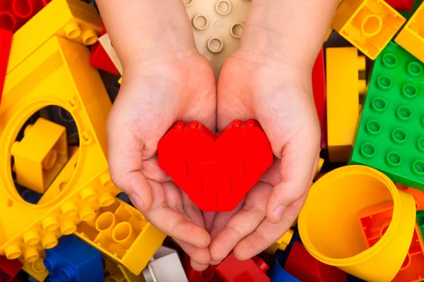 Lego red heart in child palms — Stock Photo, Image