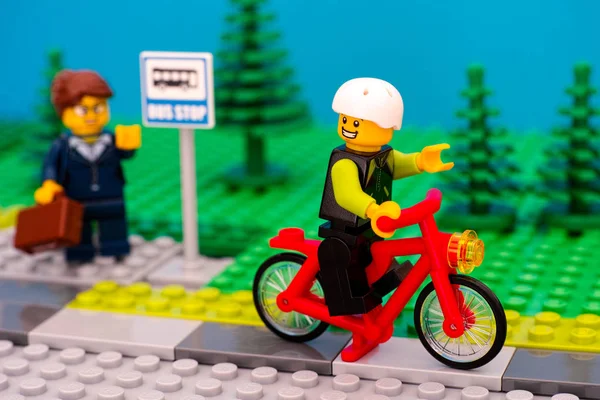 Lego niño montar en bicicleta saludando a la mujer con la maleta — Foto de Stock