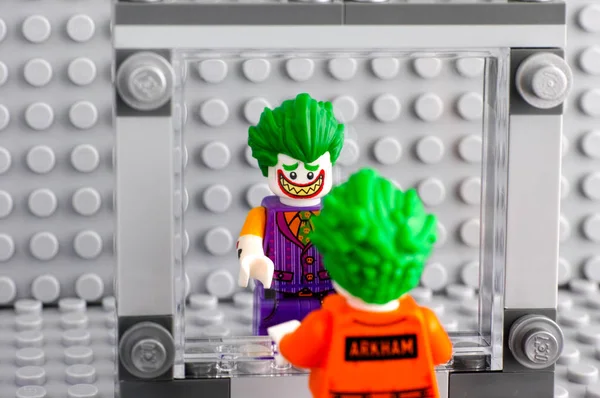 Lego Джокер в костюме Arkham смотрит на себя в зеркало и — стоковое фото
