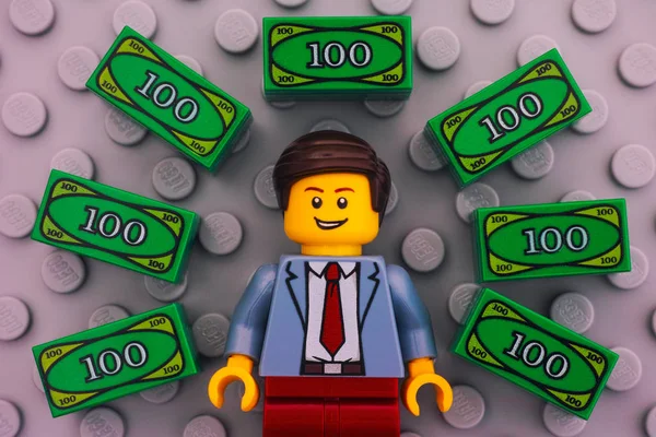 Lego businessman and Lego money on gray baseplate — Stock Photo, Image