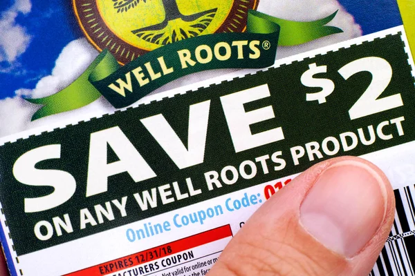 Woman finger on Well Roots discount coupon — Stock Photo, Image