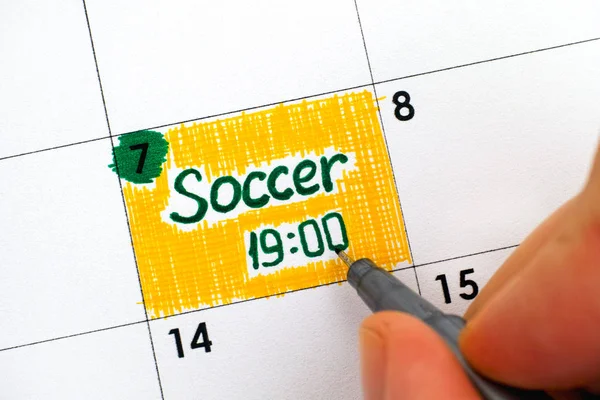 Woman fingers writing reminder Soccer in calendar