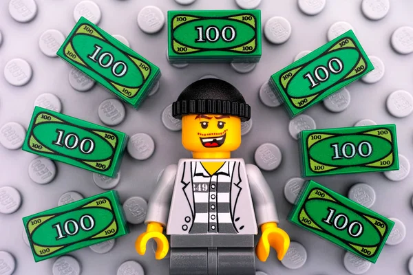 Criminoso de Lego e Lego dinheiro em fundo cinza placa base — Fotografia de Stock