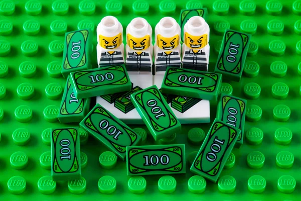 Lego ladrões microfigures com blocos de dinheiro na placa de base verde. — Fotografia de Stock