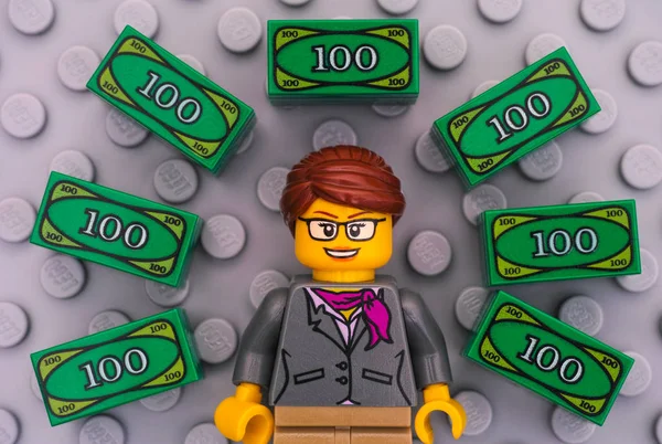 Lego business woman and Lego money on gray baseplate background — стоковое фото