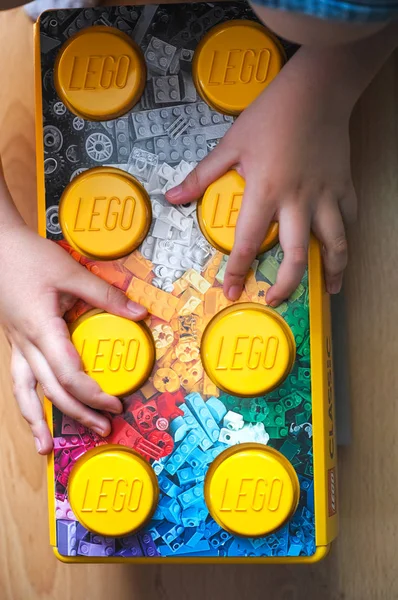 Mãos de criança com grande caixa de Lego amarelo — Fotografia de Stock