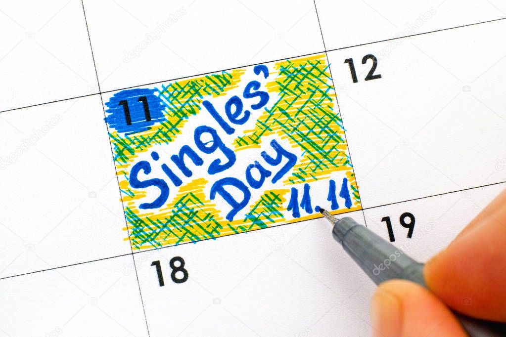 Woman fingers with pen writing reminder Singles Day 11.11 in calendar