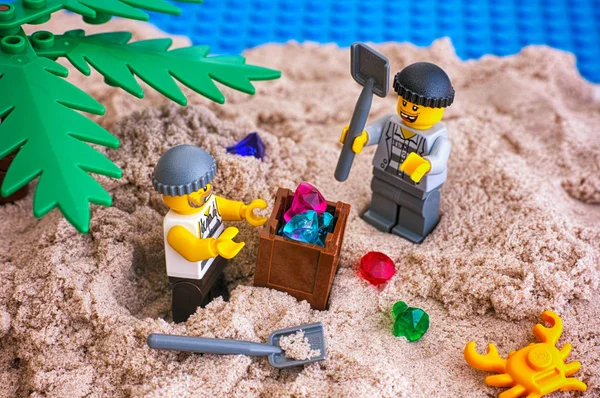Zwei Lego-Räuber graben Kiste mit Edelsteinen aus Sand auf der Insel — Stockfoto
