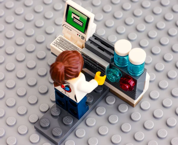 Lego scientist on her workplace with computer on gray baseplate — Stock Photo, Image