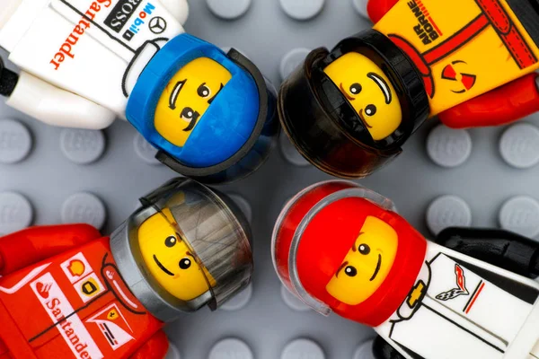Cuatro minifiguras de conductor de coche deportivo Lego en la placa base gris backgr — Foto de Stock