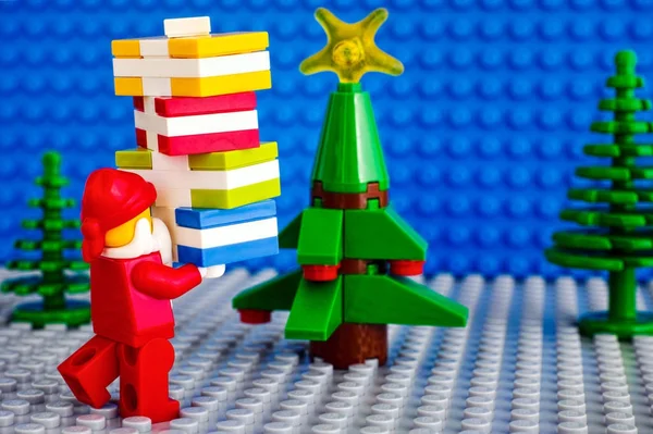 Лего Санта-Клаус с пачкой подарков возле рождественской елки — стоковое фото