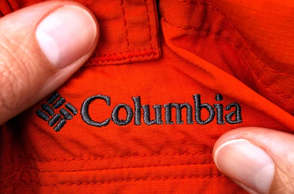 Wyszywane logo Columbia na czerwone ubrania w rękach osoby. — Zdjęcie stockowe