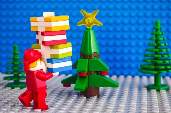 Lego Kerstman met stapel presenteert in de buurt van de kerstboom. — Stockfoto