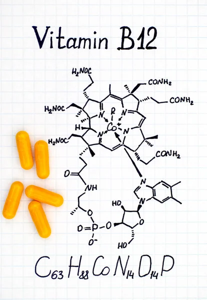 Chemische formule van vitamine B12 en gele pillen. — Stockfoto