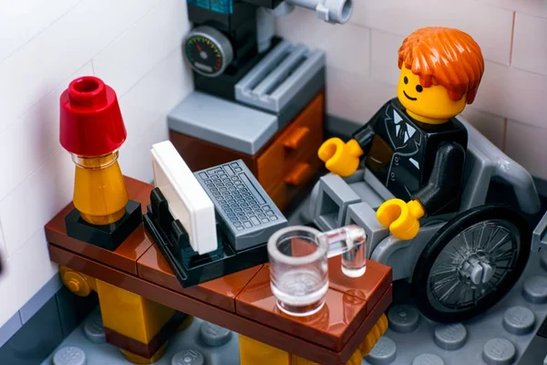 Лего офисный работник в инвалидной коляске на своем рабочем месте — стоковое фото