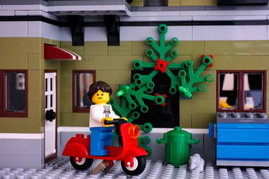 Lego kız evin arka bahçesinde üzerinde kırmızı scooter üzerinde.