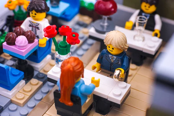 Лего пара в ресторане. Мужчина готовится сделать предложение с золотым кольцом . — стоковое фото