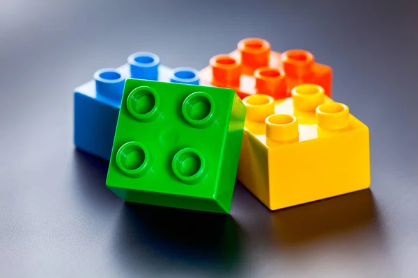 Барвисті пластикові іграшкові будівельні блоки на сірому фоні — стокове фото