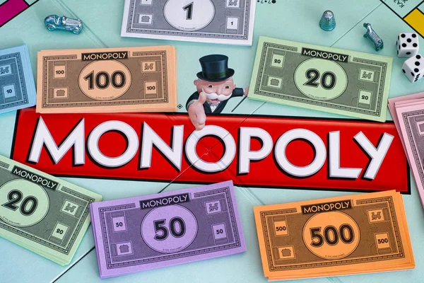 Center of Monopoly gameboard with money packs tokens and dice. — Stock Photo, Image