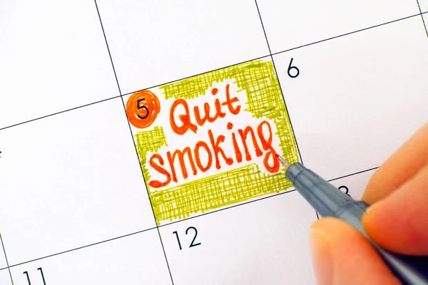 Woman fingers with pen writing reminder Quit Smoking in calendar — Stock Photo, Image
