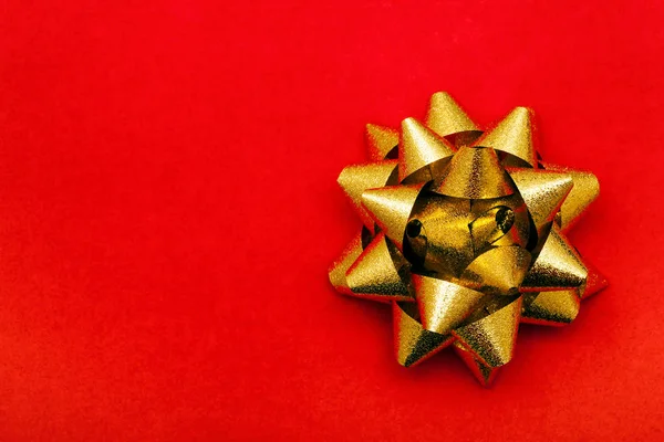 Golden gift bow on red paper background — Stock Photo, Image
