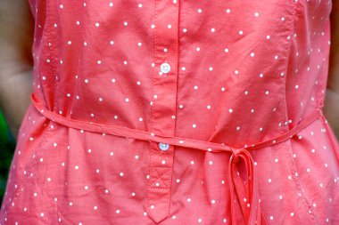 Lekeli ve kemer ile pembe elbiseli kadın.