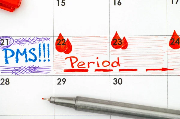 Нагадування ПМС і Період в календарі з червоною ручкою. крупним планом . — стокове фото