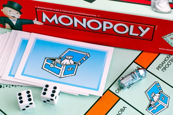 Caixa de jogo de tabuleiro de monopólio, cartões de peito comunitários, fichas, dados em — Fotografia de Stock
