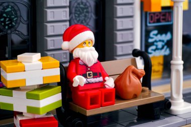 Lego Noel Baba bankta oturmuş hediyeler yığıyor.