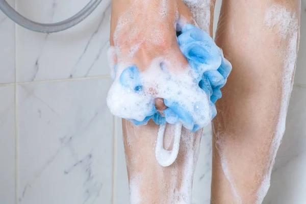 Mulher com esponja lavar as pernas no banho de chuveiro . — Fotografia de Stock