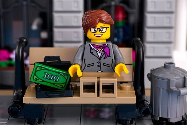 Lego businesswoman sitting on the bench with open suitcase with — Stock Photo, Image