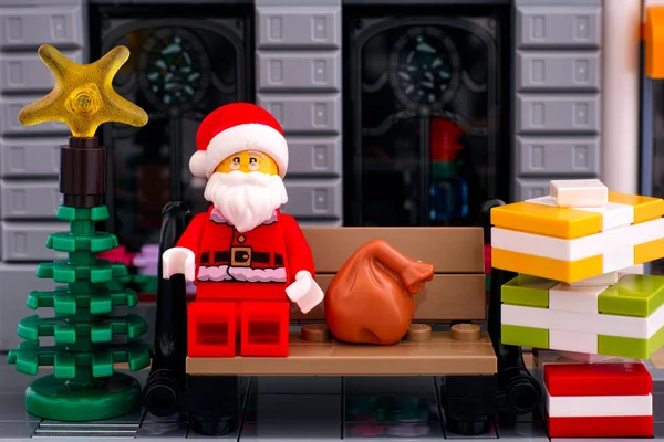 Lego Noel Baba dışarıda bankta oturuyor. Bir yığın gif ile. — Stok fotoğraf