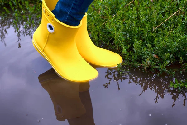 Su birikintisinde duran sarı lastik çizmeli kadın. 