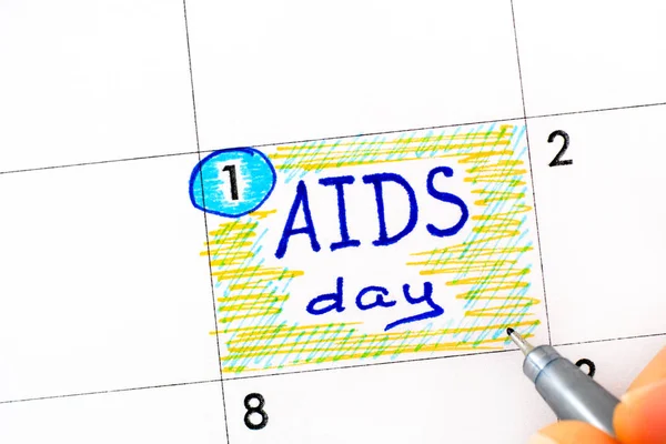 Dedos de mulher com caneta escrevendo lembrete AIDS Dia no calendário . — Fotografia de Stock
